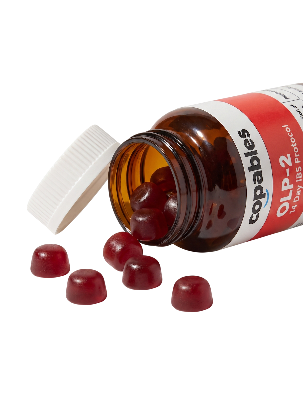 A bottle of Copables OLP gummies tipped on its side with red gummies spilling out.